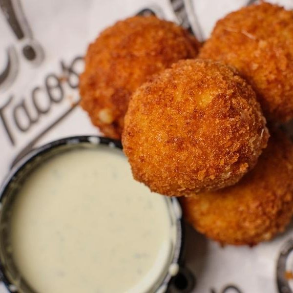 Queso Bites - Signature queso and chihuahua cheese (and a few secret ingredients) rolled up into bite-sized balls and flash fried to order. With your choice of poblano ranch or mild salsa on the side.